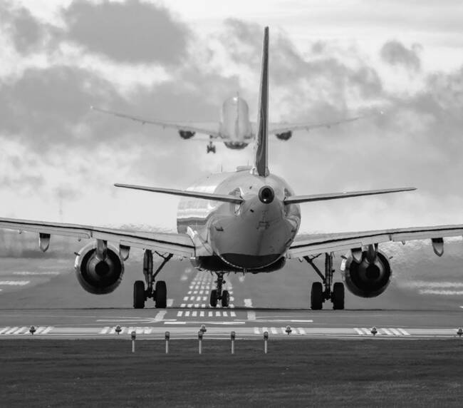 MISSISSAUGA, CANADA – OCTOBER 20, 2025: A rear view of a commercial passenger jet airliner lined up on the runway for departure at Toronto Pearson International Airport (YYZ), while another aircraft climbs into the morning sky directly ahead. The extreme 600mm telephoto perspective creates a dramatic compression effect between the two planes.